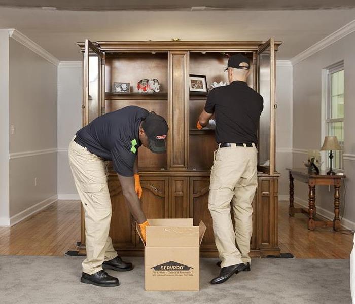 Two SERVPRO Technicians pack up a cabinet.