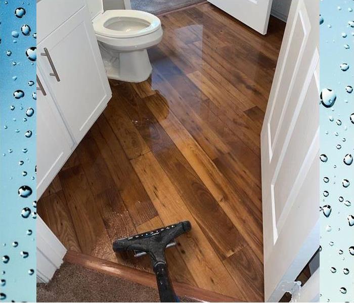 bathroom floor with water covering and an extractor removing water